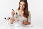 Woman cleaning a makeup brush with Veluné Aura Instant Brush Cleaner Pro