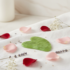 Veluné Aura Sculpting Gua Sha Stone on white linen with petals