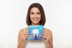 Woman holding Veluné Aura Advanced Teeth Whitening Strips packaging with radiant smile