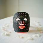 Veluné Aura LED Skin Renewal Mask on white linen with petals