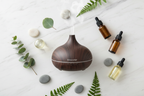 Veluné Aura Calm Mist Diffuser flat lay with pebbles, leaves and essential oils on marble