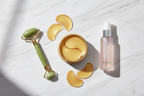 Veluné Aura Hydrating Eye Repair Patches flat lay with jade roller and rose water on marble