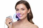 Woman smiling with bright white teeth holding Veluné Aura LED Teeth Whitening Kit