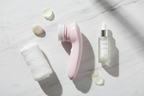 Veluné Aura Sonic Facial Cleanser flat lay with skincare accessories on marble