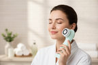 Woman holding Veluné Aura Sonic Facial Cleanser with glowing skin